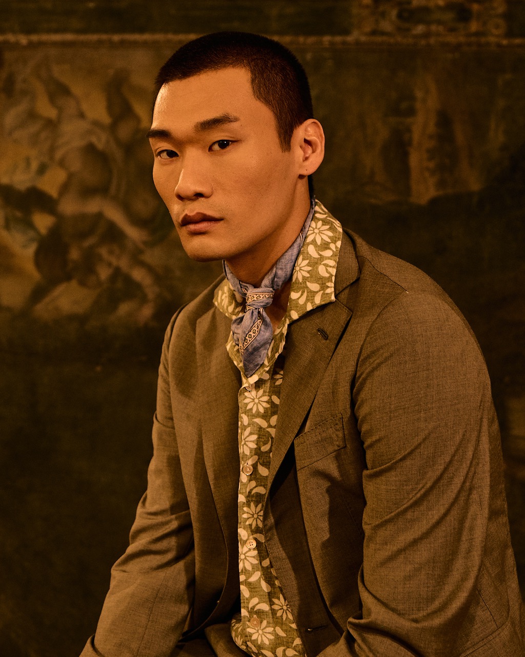 close-up of a man wearing a floral shirt and a suit against a renaissance painting